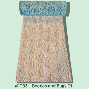 May include: A light blue rolling pin with a detailed pattern of various beetles and bugs, creating a textured design on a light beige surface. The text "#1033 - Beetles and Bugs 01" is visible at the bottom.