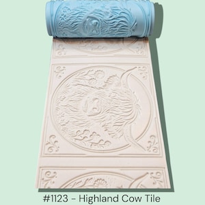 May include: A light blue patterned roller and a cream-colored tile with a Highland cow design. The roller is used to create the embossed pattern on the tile. The tile has a repeating pattern of a Highland cow surrounded by floral elements.