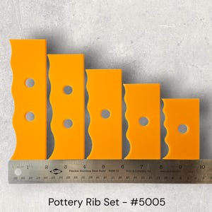 May include: A set of five orange pottery ribs with wavy edges and a circular hole. The ribs are arranged in descending order of size, with a ruler at the bottom. The text "Pottery Rib Set - #5005" is below the ribs.