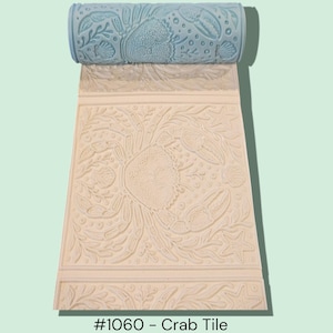May include: A light blue roller with a crab and seashell pattern, unrolling to reveal a cream-colored tile with a matching crab design. The tile is labeled "#1060 - Crab Tile".