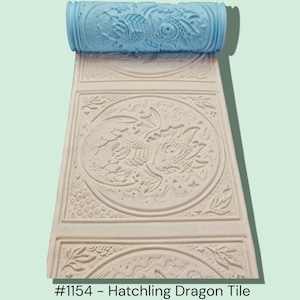 May include: A light blue patterned roller above a cream-colored tile with a dragon design. The tile has a repeating pattern of circular dragon images and floral accents. The text "#1154 - Hatchling Dragon Tile" is at the bottom.