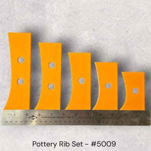 May include: A set of five orange pottery ribs of varying sizes, each with a curved edge and a circular hole. A metal ruler with inch measurements is placed below the ribs. The text "Pottery Rib Set - #5009" is at the bottom.