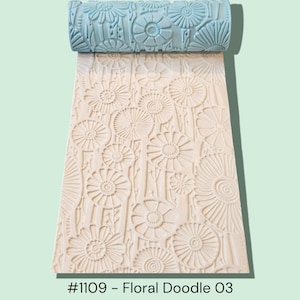 May include: A light blue floral pattern rolling tool with a matching embossed design on the rolled-out surface. The tool is used to create a textured floral pattern. The text "#1109 - Floral Doodle 03" is visible at the bottom.
