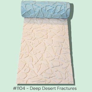 May include: A light blue textured roller sits atop a cream-colored surface with a fractured pattern. The roller's design matches the pattern below, creating a repeating texture. The text "#1104 - Deep Desert Fractures" is at the bottom.