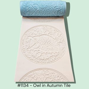 May include: A light blue roller with an owl design, creating an embossed pattern on a white surface. The pattern features an owl in a circular frame with autumn leaves. The text "#1134 - Owl in Autumn Tile" is at the bottom.