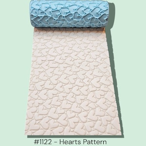 May include: A light blue rolling pin with a heart pattern is shown partially rolled out on a white surface with the same heart pattern. The text "#1122 - Hearts Pattern" is at the bottom of the image.