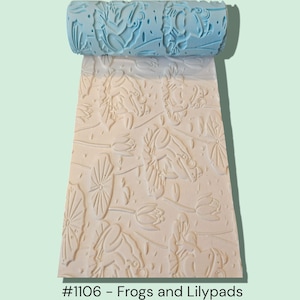 May include: A blue textured roller with a repeating pattern of frogs and lily pads, creating an embossed design on a light-colored surface. The text "#1106 - Frogs and Lilypads" is at the bottom.