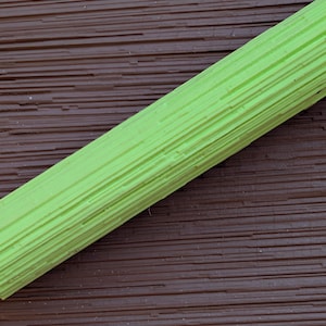 May include: A vibrant green, textured, cylindrical object, possibly a foam roller or similar exercise tool, is placed diagonally against a brown, ridged surface. The object's surface has parallel lines.