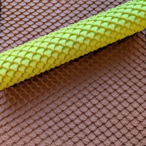 May include: A textured brown surface with a scale-like pattern, and a bright green, cylindrical object with a similar scale pattern. The patterns are reminiscent of reptile skin or a textured roof.