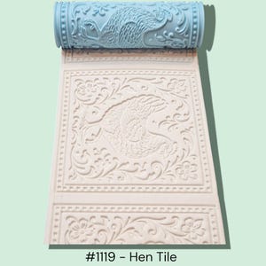 May include: A light blue textured roller with a hen design, unrolled onto a white surface with a matching hen and floral pattern. The text "#1119 - Hen Tile" is at the bottom.
