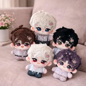 Puede incluir: Cinco muñecos de peluche con diferentes colores de pelo: marrón, blanco, negro y morado. Cada muñeco tiene un diseño floral en el pelo y viste un atuendo claro con tirantes. Los muñecos tienen ojos grandes y expresivos y mejillas rosadas.