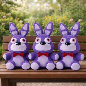 Pode incluir: Três coelhos de pelúcia roxos com olhos grandes, gravatas borboleta vermelhas e barrigas brancas sentados em um banco de madeira. Os coelhos têm orelhas compridas e estão lado a lado.