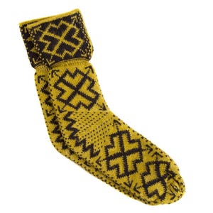 Puede incluir: Un par de calcetines de color amarillo mostaza con un patrón geométrico negro repetido. Los calcetines están doblados en la parte superior y están hechos de un material de punto. El diseño presenta un motivo en forma de cruz.