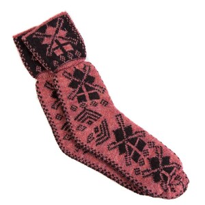 Puede incluir: Un par de calcetines de punto en color rosa polvoriento con un patrón geométrico negro. Los calcetines tienen un puño doblado y están diseñados para brindar calidez y comodidad. El patrón incluye formas de diamantes y cruces.