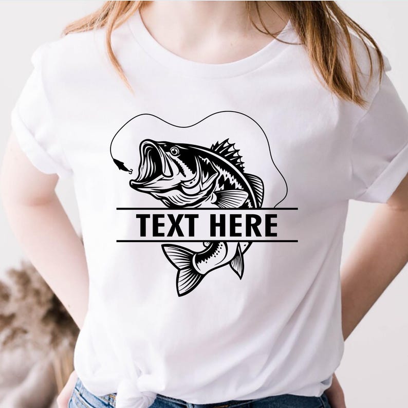 May include: White t-shirt featuring a black and white graphic of a largemouth bass with an open mouth, hook, and line. The text "TEXT HERE" is displayed below the fish design. The shirt is a casual wear item.