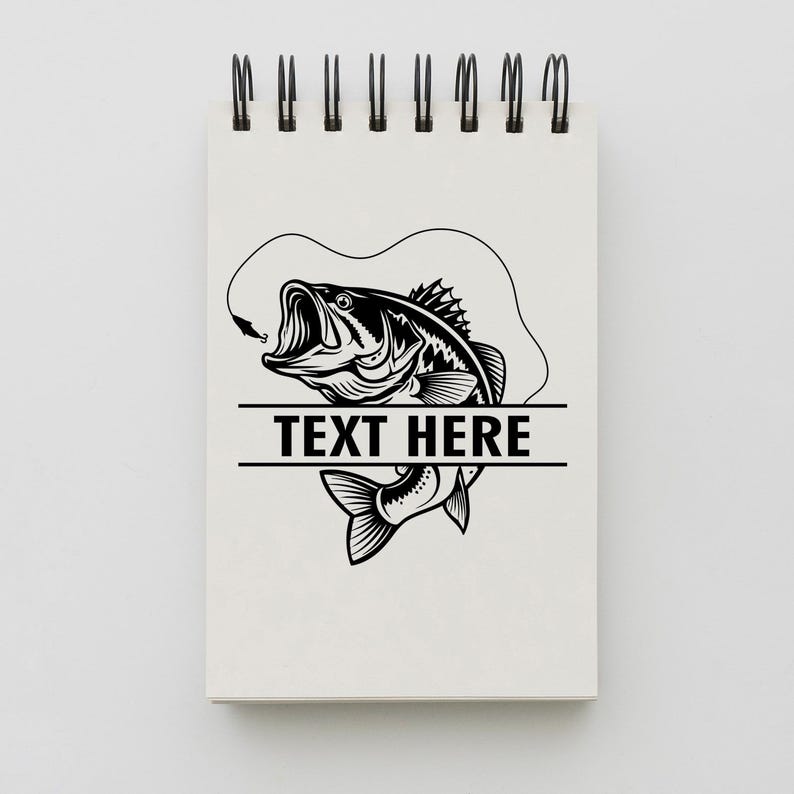 May include: A spiral-bound notepad with a black and white illustration of a largemouth bass with a hook in its mouth. The text "TEXT HERE" is displayed in a horizontal rectangle below the fish.