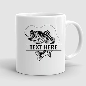 May include: White ceramic mug featuring a black and white illustration of a largemouth bass with an open mouth, a fishing hook, and the text "TEXT HERE" in a bold font. The mug has a curved handle.