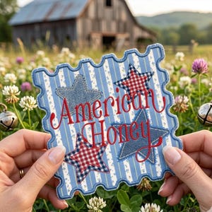 May include: A patriotic, square-shaped patch with a scalloped edge. The patch features a blue and white striped background with four stars, two denim and two red gingham. The words "American Honey" are embroidered in red.