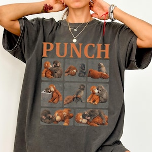 May include: Dark gray t-shirt with the word "PUNCH" in orange block letters. The shirt features a grid of nine squares, each containing a different illustration of monkeys. The monkeys are in various poses, some hugging and some sitting.