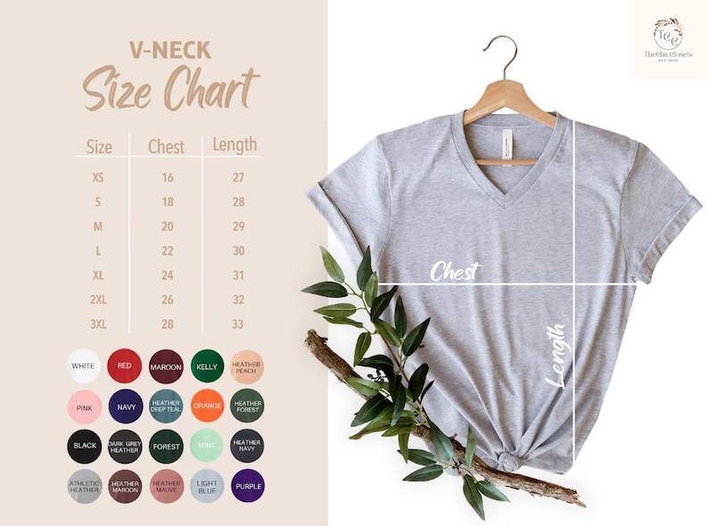 Puede incluir: Una camiseta gris claro con cuello en V colgada de una percha de madera, con una tabla de tallas y opciones de color a la izquierda. La tabla de tallas muestra las medidas de pecho y largo. La camiseta est&aacute; anudada en la parte inferior.