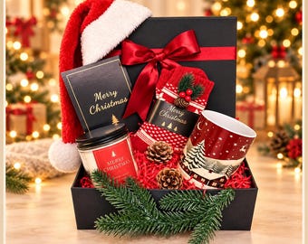 May include: A black gift box containing a red Santa hat, a candle with a Merry Christmas label, red patterned socks, a mug with a winter landscape, and two pinecones, all nestled on red paper shreds with a pine branch accent.