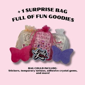 Op de afbeelding: Op een roze achtergrond drie organza zakjes gevuld met goodies, geflankeerd door een roze en een paarse vlinder-vormige pluche. De zakjes bevatten stickers, tijdelijke tattoos en zelfklevende edelstenen. Tekst luidt: "+ 1 SURPRISE BAG FULL OF FUN GOODIES."