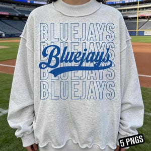 Peut inclure: Un sweat-shirt gris clair avec le mot "BLUEJAYS" en lettres bleues répétées verticalement. Le mot "Bluejays" est également écrit en cursive. Le sweat-shirt a un col rond et un ourlet légèrement vieilli.