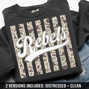 May include: A charcoal gray crewneck sweatshirt featuring a central graphic of vertical stripes with a camouflage pattern. Overlaid on the stripes is the word Rebels in a white, distressed, cursive script font. The garment has a ribbed collar.