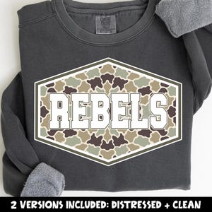 May include: A charcoal gray crewneck sweatshirt featuring a large hexagonal graphic on the chest. The graphic contains a camouflage pattern in shades of brown, tan, and sage green with the word REBELS printed in bold white block letters.
