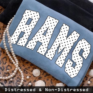 Puede incluir: Un textil azul claro con la palabra "RAMS" en letras blancas grandes con lunares negros. El texto está en una fuente en negrita, colegial. Las palabras "Distressed & Non-Distressed" están en la parte inferior de la imagen.