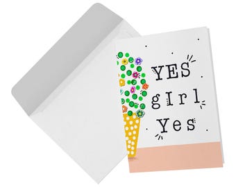 May include: A white greeting card with a yellow polka-dot cone topped with green circles and colorful flowers, featuring the black text YES girl Yes. The card is positioned next to a matching white envelope on a plain white background.