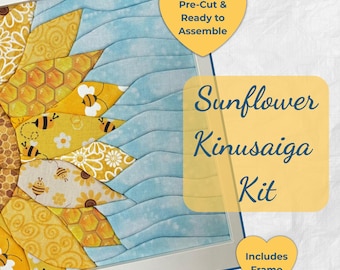 May include: A Kinusaiga kit featuring a sunflower design with yellow and white fabric pieces, including bees and honeycomb patterns, set against a light blue wavy background. The kit includes a frame, with text reading Sunflower Kinusaiga Kit.