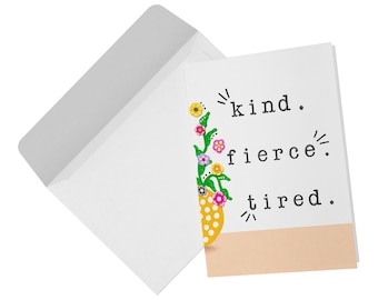 May include: A white greeting card with a matching envelope featuring the text kind. fierce. tired. in black typewriter font. A yellow vase with white polka dots and colorful floral stems is illustrated on the left side of the card.
