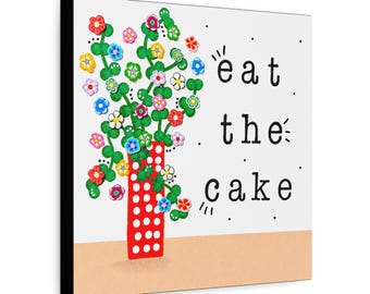 May include: A square wall art print featuring a red vase with white polka dots containing green stems with colorful small flowers. The text "eat the cake" is printed in black typewriter-style font on the right side against a white background.