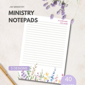 May include: A white lined notepad featuring a watercolour floral border at the bottom with purple, yellow, and blue flowers. The text reads JW MINISTRY MINISTRY NOTEPADS, 3 DESIGNS, 40 SHEETS, and TO LEARN MORE VISIT JW.ORG. A gold pen is visible.