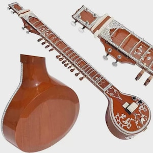 May include: A brown sitar, a long-necked stringed instrument, with intricate white inlay designs. The instrument features a rounded body and a long fretboard with multiple strings and tuning pegs. The sitar is a traditional Indian musical instrument.