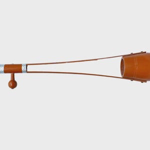 May include: A brown Ravanahatha, a traditional Indian musical instrument, with a cylindrical body and a long, slender neck. The instrument has a red accent on the body and a silver-coloured section near the neck's end. The strings extend from the body to the neck.