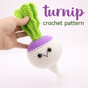 Peut inclure: Un jouet de navet crocheté avec un visage souriant, des feuilles vertes et un dessus violet. Le navet est blanc avec des yeux en perles noires et une bouche cousue. Le texte "turnip crochet pattern" est en haut à droite.