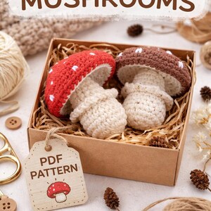 Könnte beinhalten: Zwei gehäkelte Pilzfiguren mit roten und braunen Kappen, weißen Punkten und cremefarbenen Stielen, eingebettet in einer Pappschachtel mit Stroh. Das Bild enthält den Text "CROCHET PATTERN MUSHROOMS" und ein Etikett mit der Aufschrift "PDF PATTERN".