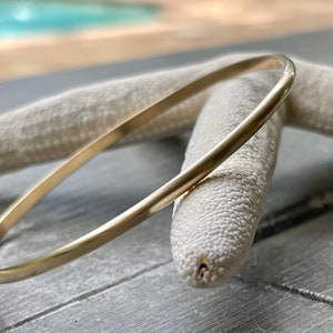 May include: A simple gold bangle bracelet, a classic piece of jewelry.