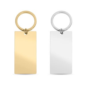 May include: Two rectangular keychains, one in a polished gold-tone finish and one in a polished silver-tone finish. Each keychain features a flat, smooth metal tag attached to a circular split ring by a small jump ring, providing a simple design.