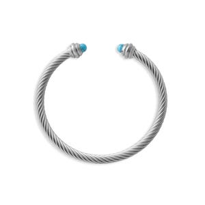 A silver twisted cable cuff bracelet with turquoise ends displayed on a white background, alongside small color swatch icons in the bottom corner.
