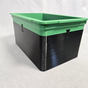 Puede incluir: Contenedor de almacenamiento rectangular de dos tonos. La secci&oacute;n superior es verde, la inferior es negra. El contenedor tiene un dise&ntilde;o simple y funcional, adecuado para diversas necesidades de almacenamiento.