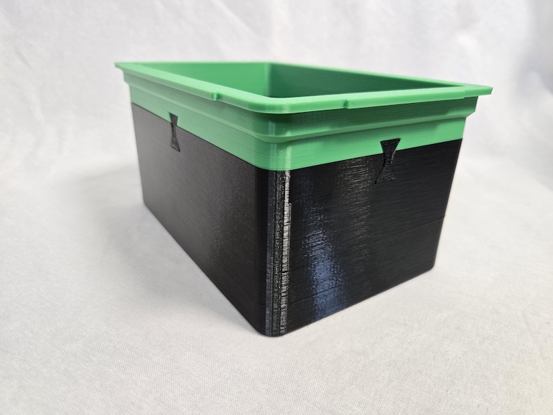 Puede incluir: Contenedor de almacenamiento rectangular de dos tonos. La secci&oacute;n superior es verde, la inferior es negra. El contenedor tiene un dise&ntilde;o simple y funcional, adecuado para diversas necesidades de almacenamiento.