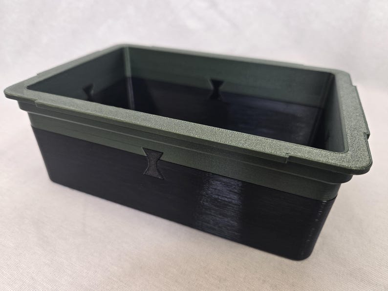 Puede incluir: Un contenedor rectangular de dos tonos. El borde superior es verde oscuro texturizado, mientras que la parte inferior es negra. El contenedor tiene un dise&ntilde;o simple y utilitario, con un acabado liso y una forma rectangular.