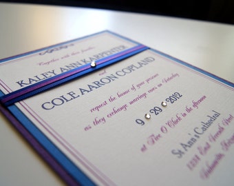 May include: A wedding invitation with a purple and blue ribbon tied around it. The invitation is for Kaley Ann Karpeter and Cole Aaron Copland, and the wedding is on September 29, 2012 at Five O'Clock in the afternoon at St. Ann's Cathedral.