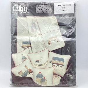 May include: A craft kit for making a set of 10 toy pillows. The kit includes a 12" x 12" pillow with a steam engine design, and nine smaller pillows with various designs, including a rocking horse, a house, a wagon, and a well. The kit includes fabric, thread, batting, and instructions. The kit is from Cathy Needlecraft Inc.