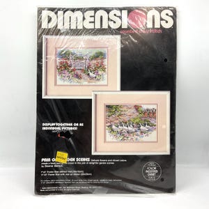 May include: A Dimensions counted cross stitch kit titled Pair of Garden Scenes by Dawna Barton. The packaging features two framed garden illustrations with flowers and geese. It includes specifications for 7x5 inch and 11x9 inch frame sizes.