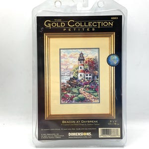 May include: A cross stitch kit featuring a lighthouse with a path leading to it. The kit is titled "Beacon at Daybreak" and is part of the "Gold Collection Petites" line. The kit includes 18 count ivory Aida, needle, and easy instructions. The finished size is 5 x 7 inches.
