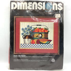 May include: A needlepoint kit featuring a still life of peaches in a basket, a duck, a pitcher, and flowers. The kit is titled "Posies and Peaches" and is by artist Charles Wysocki. The kit is 14 x 11 inches.
